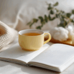 🌨️ Kleine Gesten im Winter – warum sie uns mehr wärmen als jede Heizung (und wie du sie bewusst leben kannst) Gemütliche Winterstimmung mit einer Tasse Tee, einem offenen Notizbuch, einer brennenden Kerze und einer weichen Decke – ruhiger Moment für Selbstfürsorge.