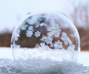 Gefrorene Seifenblase mit zarten Frostmustern – ein kleines Winterwunder in der Natur.